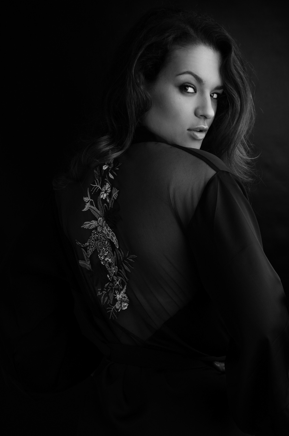 Portrait boudoir en noir et blanc, femme en dentelle noire regardant par-dessus son épaule